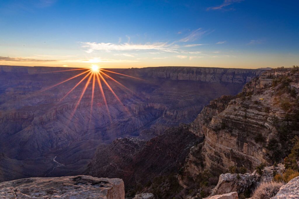 A sunstar gleams and the ridges and layers of the Grand Canyon are revealed with the rising sun