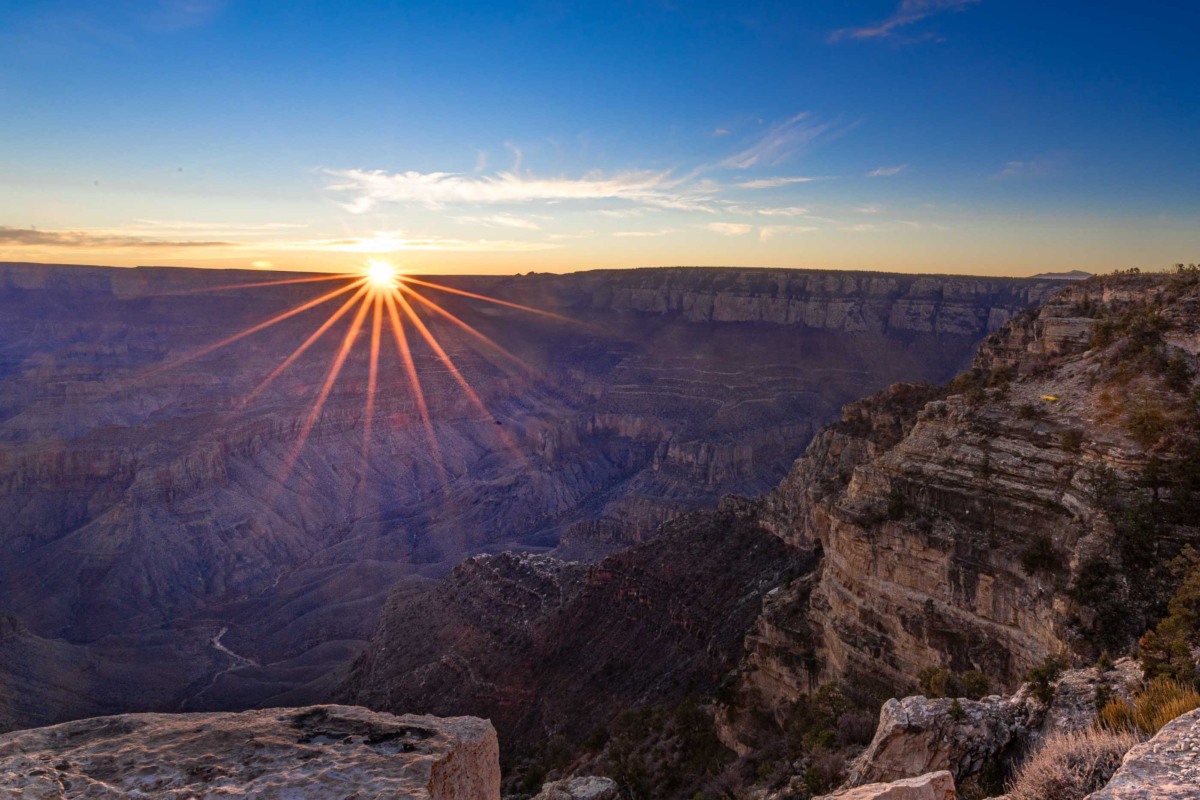 A sunstar gleams and the ridges and layers of the Grand Canyon are revealed with the rising sun