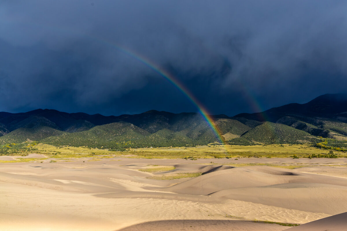 Rainbow over Great Sand Dunes with storm clouds and dune lines