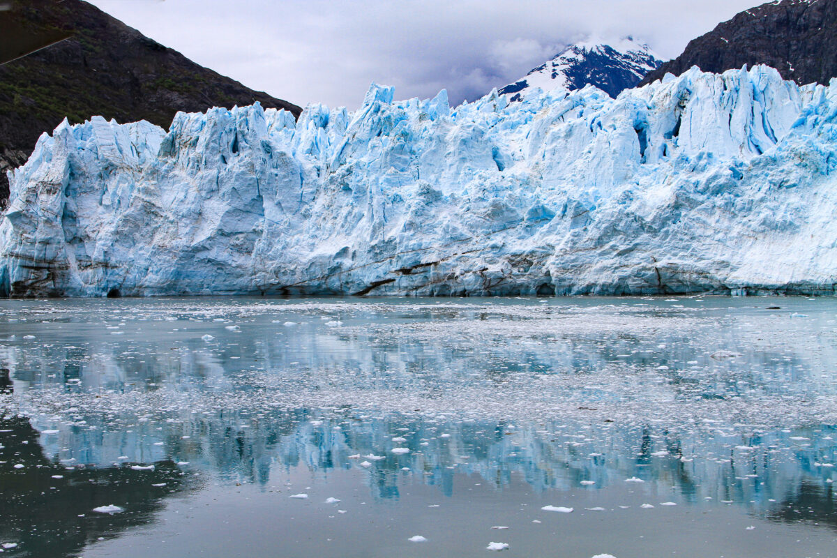 Alaska glacier with bright blue ice and reflection on calm water