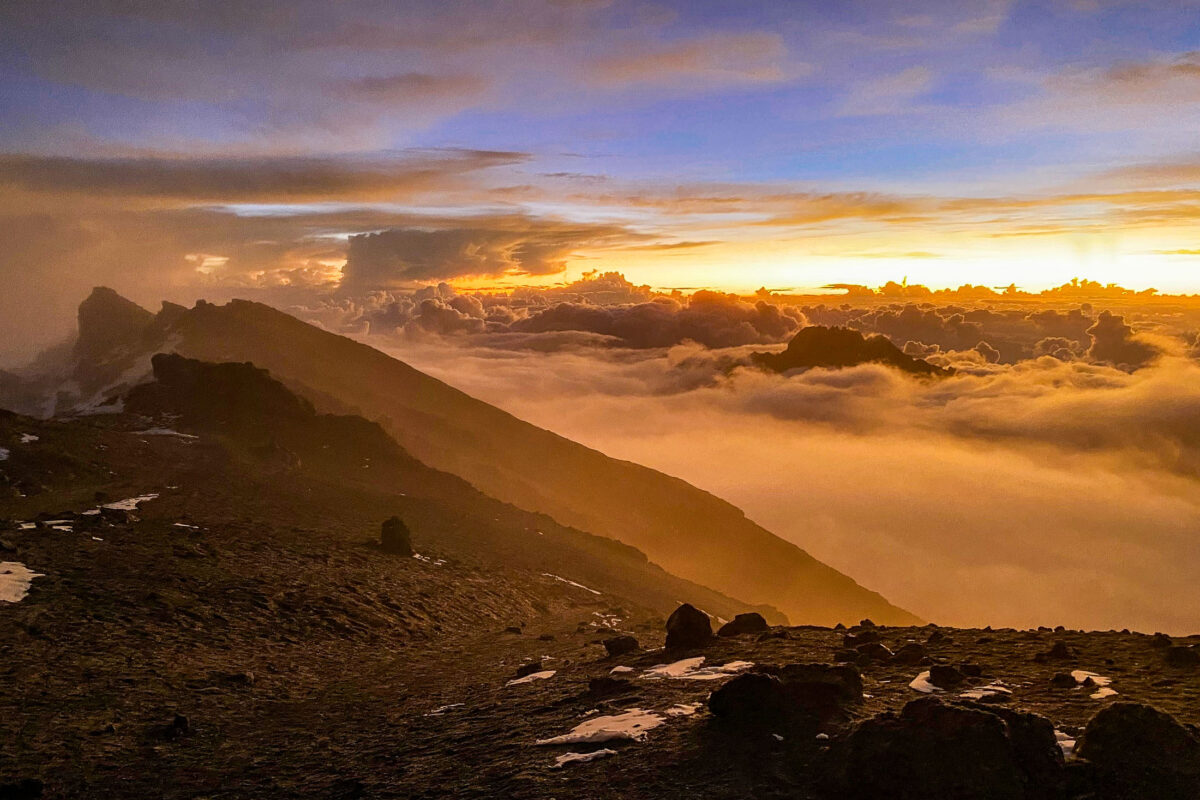 Sunrise on the crater rim of Mount Kilimanjaro between Stella Point and the summit above clouds