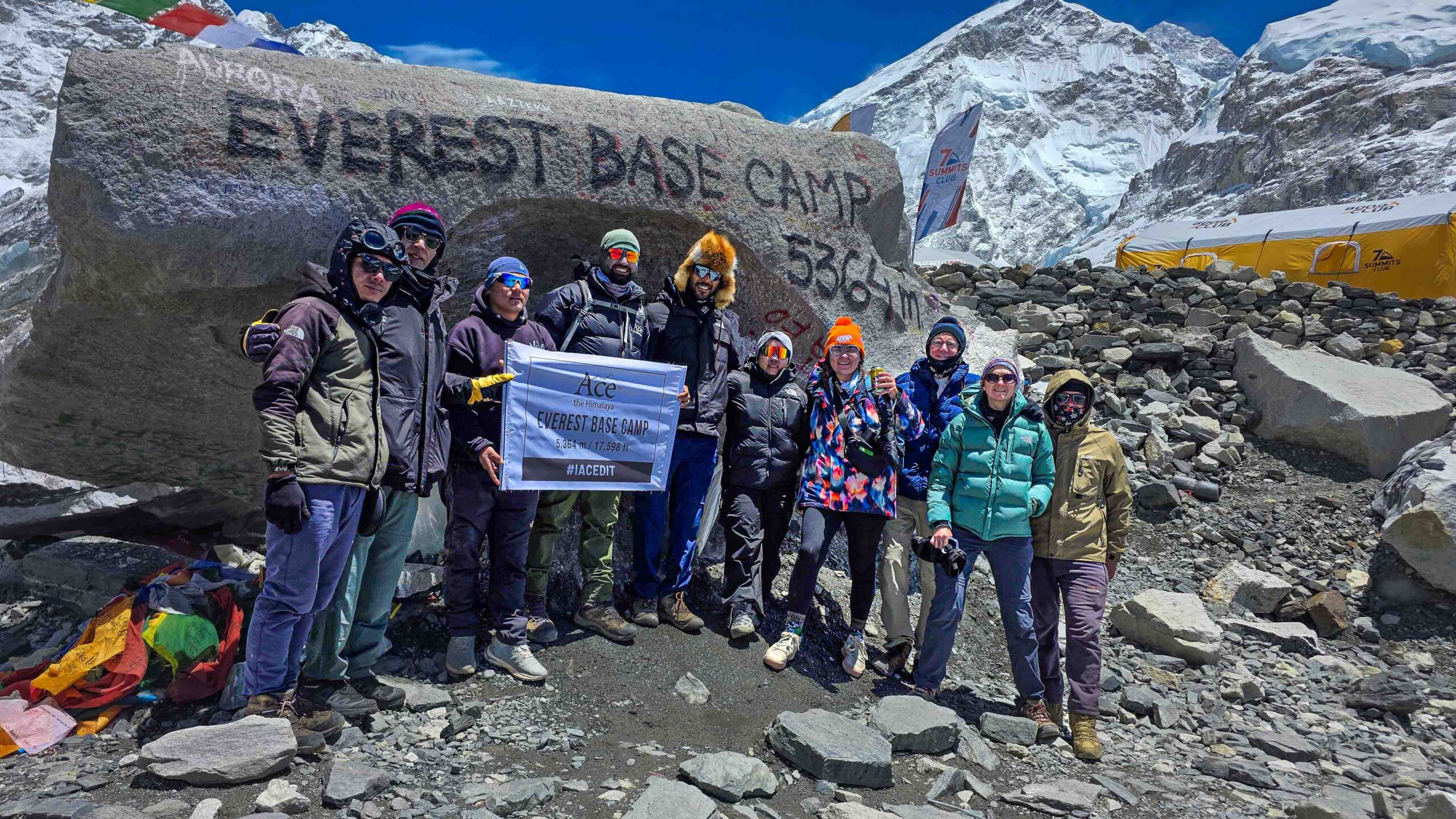 Team photo at the iconic Everest Base Camp rock in Nepal