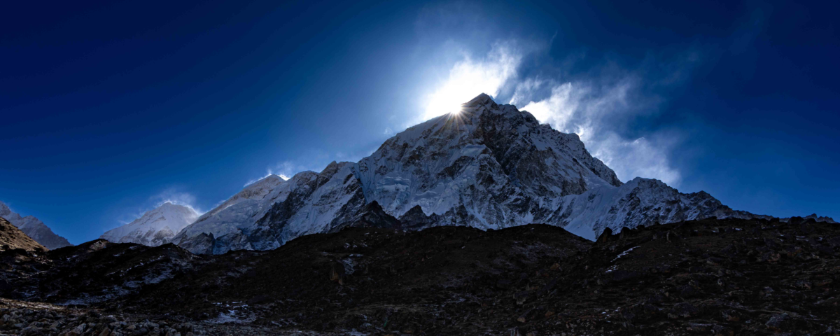 A dramatic sunstar emerges above the Himalayan peaks of Nuptse during sunrise in Nepal’s Everest region
